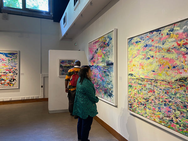 visitors view Chloe Tinsley's artwork of the Fal Bay, the Helford Sunrise, and Helford Sunset at the exhibition The Colour Bath, Safe Haven in Vibrance at Trebah Garden, green painting, Trebah art, cornish art, cornish artist, cornish artists,